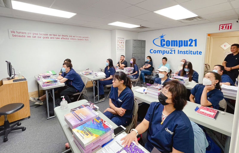 Students in medical uniforms attending a class at Compu21 Institute