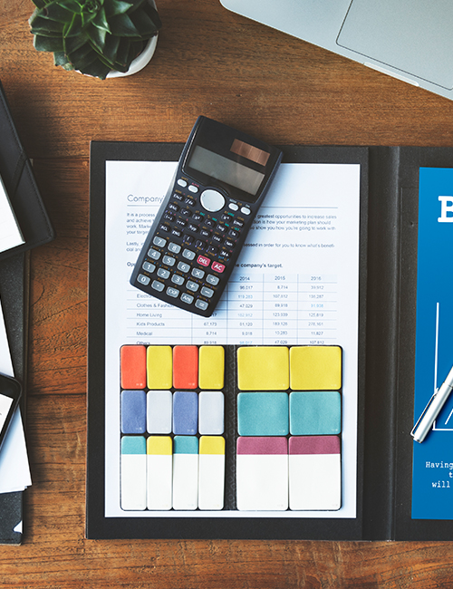 Scientific calculator on financial report with colorful data analysis charts on a desk